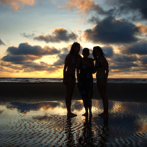 Silhouettes of three women in fellowship near the sea