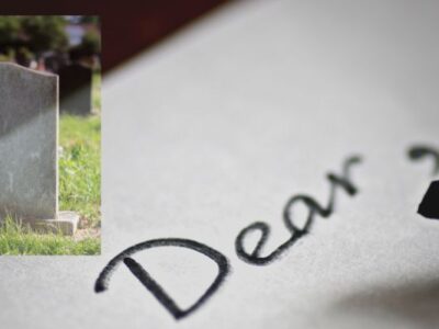 Writing to the deceased: Pen writing letter with tombstone in background