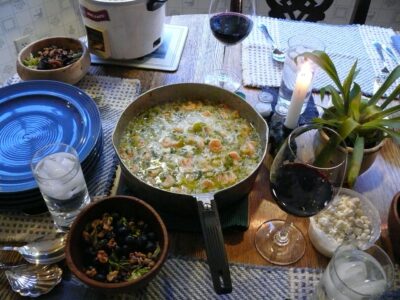 A saucepan of shrimp etouffee on the table with other table settings.
