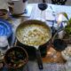 A saucepan of shrimp etouffee on the table with other table settings.