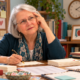 Elizabeth lat her desk ooks busy with no extra time - clock on wall